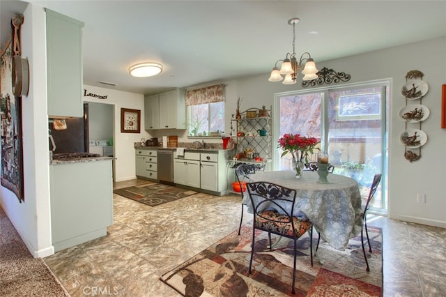 kitchen featuring decorative light fixtures, stainless steel dishwasher, washer / clothes dryer, sink, and an inviting chandelier