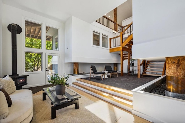 living room featuring a wood stove, a towering ceiling, and hardwood / wood-style flooring