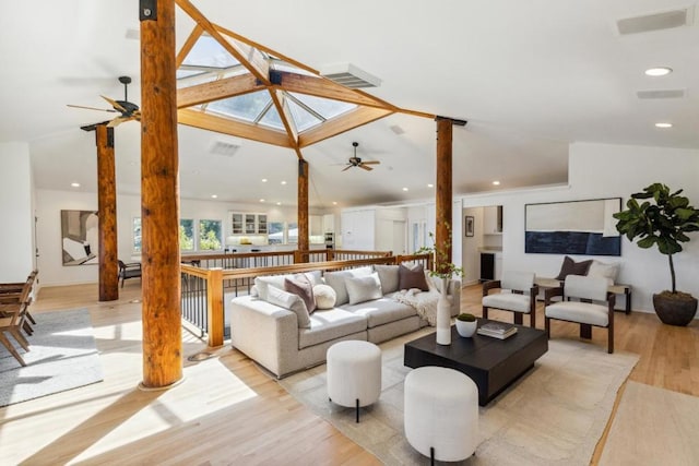 living room featuring high vaulted ceiling, light wood-type flooring, ceiling fan, and ornate columns