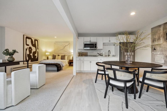 dining area featuring sink, a baseboard heating unit, and light wood-type flooring