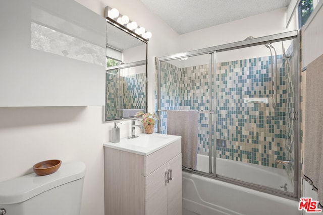 full bathroom with bath / shower combo with glass door, toilet, vanity, and a textured ceiling