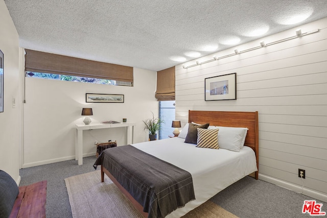 carpeted bedroom with a textured ceiling and wood walls