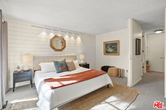 bedroom with light carpet, a textured ceiling, and wooden walls