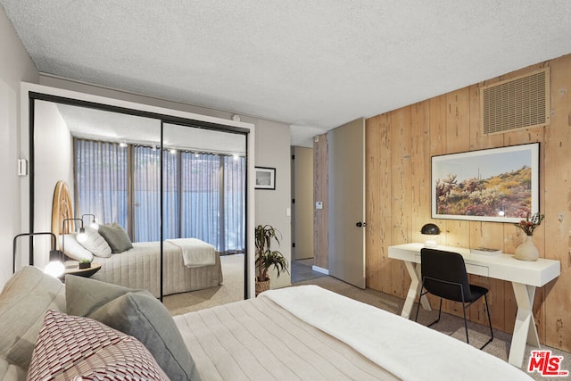 carpeted bedroom featuring a textured ceiling, a closet, and wooden walls