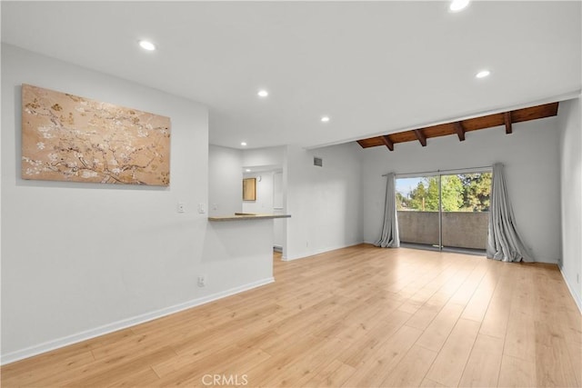 unfurnished living room with light hardwood / wood-style flooring and beamed ceiling