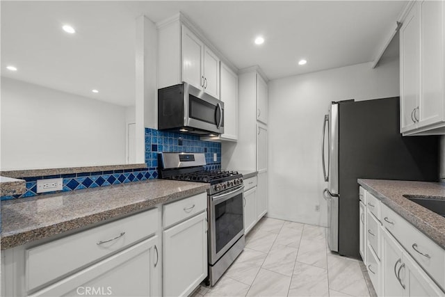 kitchen with stone counters, appliances with stainless steel finishes, backsplash, and white cabinetry