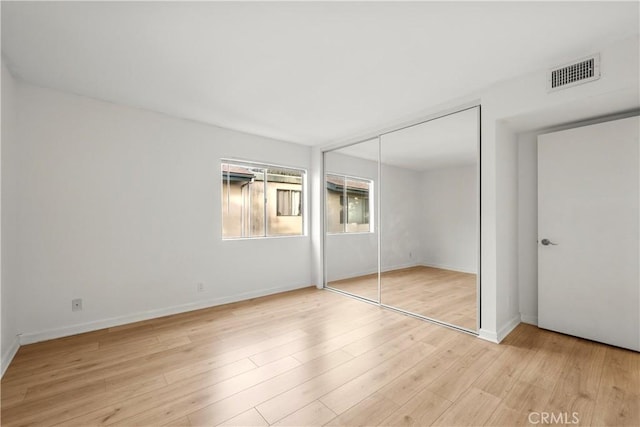 unfurnished bedroom with a closet and light hardwood / wood-style floors