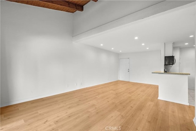 unfurnished living room featuring beam ceiling, wooden ceiling, and light hardwood / wood-style floors