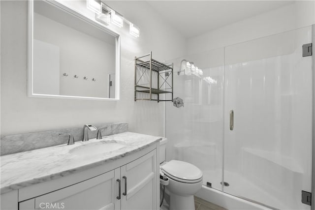 bathroom featuring a shower with door, toilet, and vanity