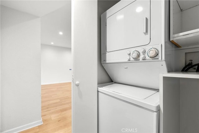 laundry area featuring stacked washing maching and dryer and light wood-type flooring