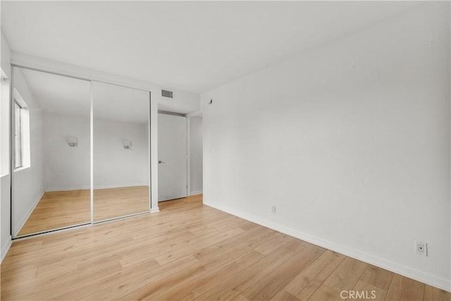 unfurnished bedroom featuring light wood-type flooring and a closet