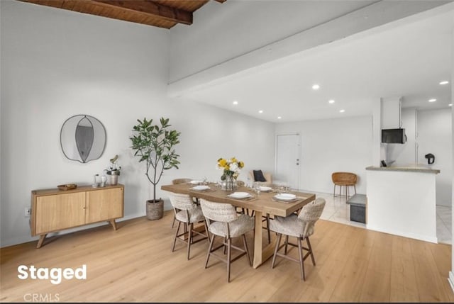 dining space with light wood-type flooring, wooden ceiling, and beamed ceiling