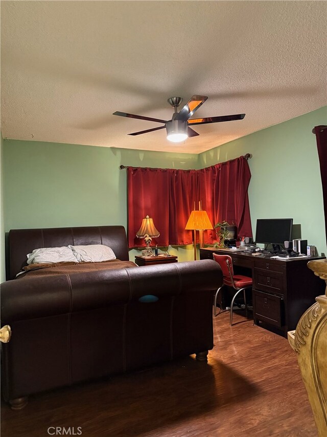 bedroom with ceiling fan, wood-type flooring, and a textured ceiling