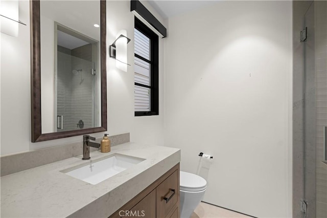 bathroom with toilet, vanity, and a shower with shower door