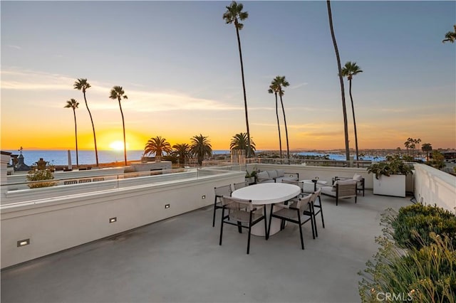 patio terrace at dusk featuring a water view and outdoor lounge area