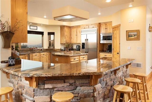 kitchen with a peninsula, a kitchen bar, and built in appliances