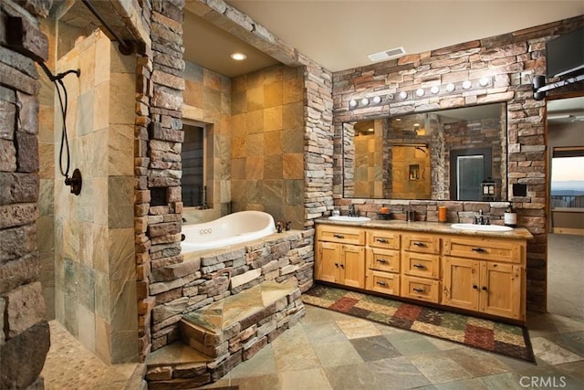 bathroom with double vanity, a relaxing tiled tub, a sink, and visible vents