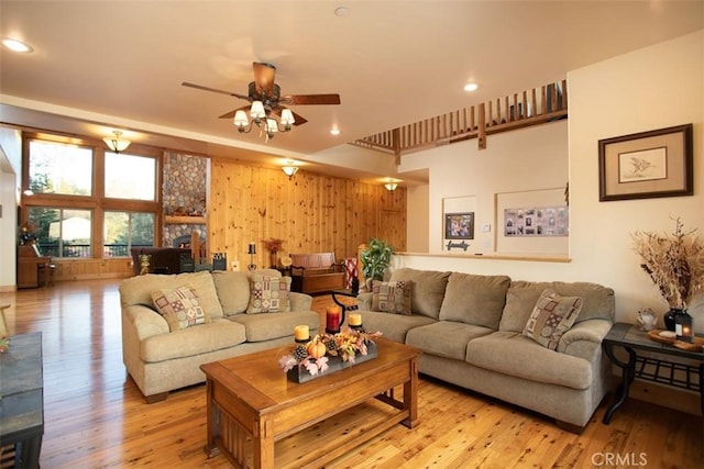 living room featuring a ceiling fan, recessed lighting, wood walls, and light wood finished floors