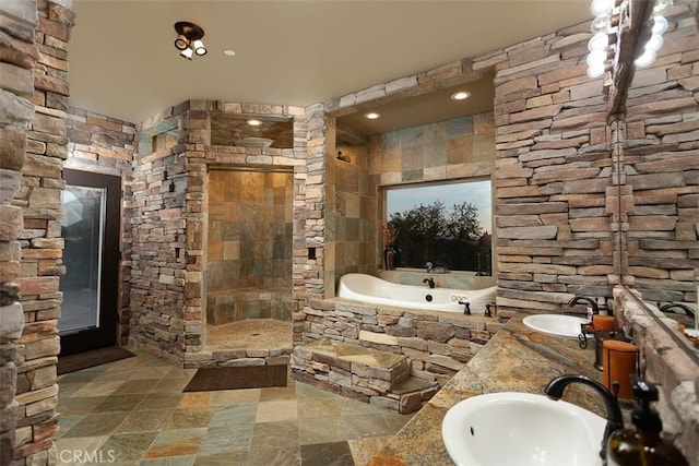 full bath featuring a garden tub, double vanity, tiled shower, and a sink