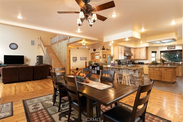 dining room with light wood-type flooring, visible vents, stairway, and a ceiling fan