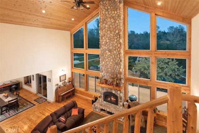 living room with a ceiling fan, wood ceiling, wood finished floors, a fireplace, and high vaulted ceiling