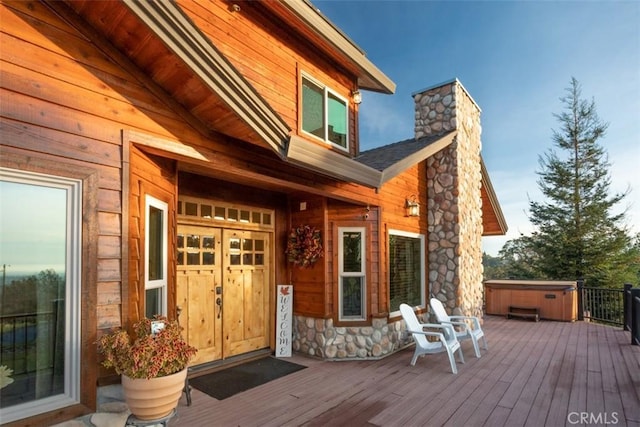 exterior space featuring a hot tub, a chimney, and a wooden deck