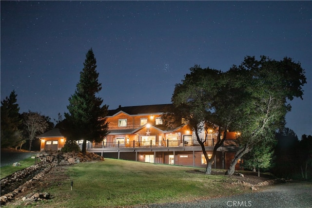 back of house at twilight featuring a lawn