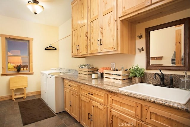 clothes washing area with independent washer and dryer, a sink, cabinet space, and baseboards