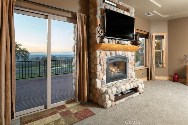 interior space featuring a stone fireplace, carpet, visible vents, and baseboards