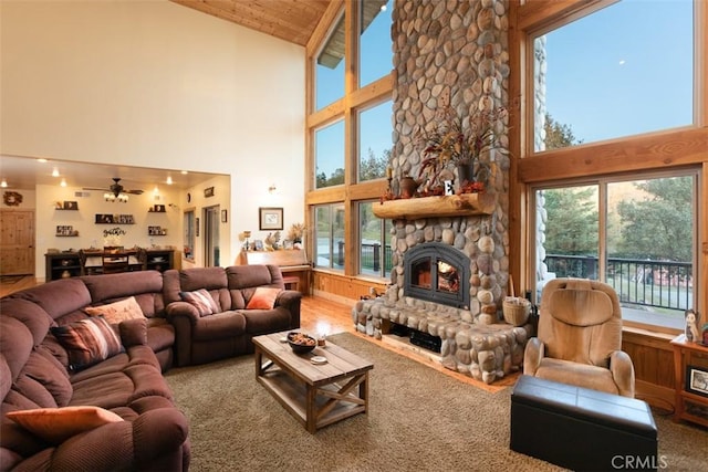 living area with wood ceiling, a healthy amount of sunlight, a fireplace, and a towering ceiling