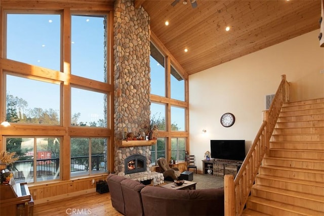 living room with high vaulted ceiling, a fireplace, wood ceiling, stairs, and light wood finished floors