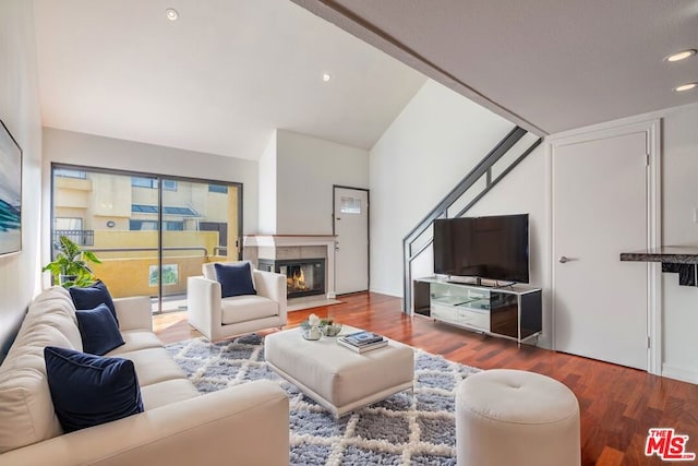 living room with hardwood / wood-style flooring, lofted ceiling, and a tiled fireplace