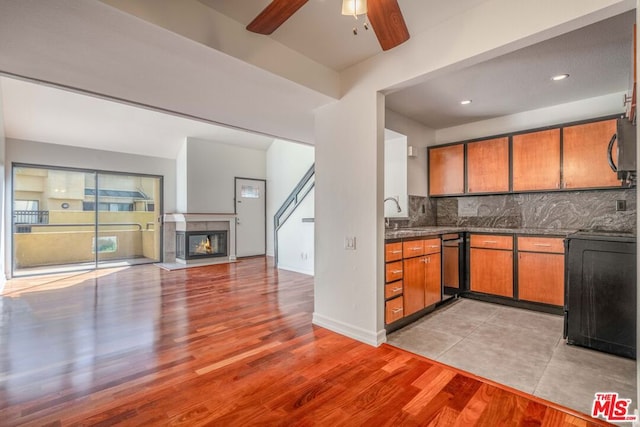 kitchen with light hardwood / wood-style floors, ceiling fan, black dishwasher, decorative backsplash, and stove