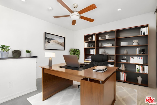 carpeted home office featuring ceiling fan