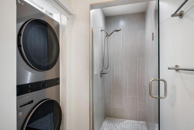 bathroom with stacked washer / dryer and a shower with shower door