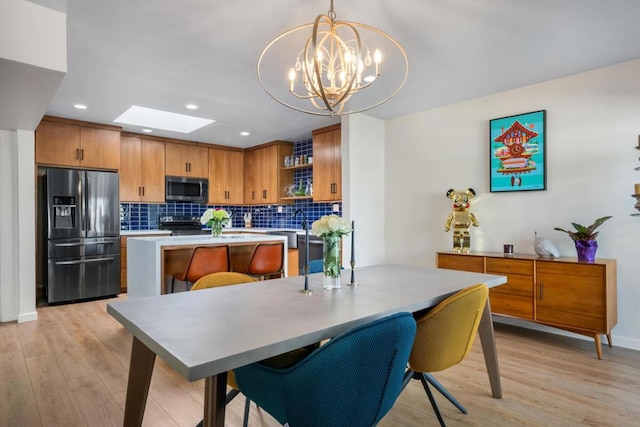 dining area featuring an inviting chandelier, a skylight, and light wood-type flooring