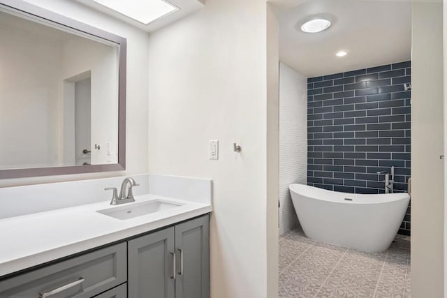 bathroom featuring tile patterned flooring, vanity, a bath, and tile walls