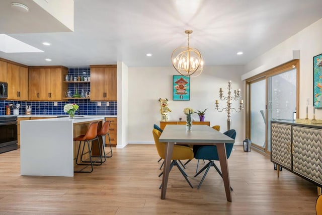 kitchen with backsplash, hanging light fixtures, electric range, a notable chandelier, and light wood-type flooring