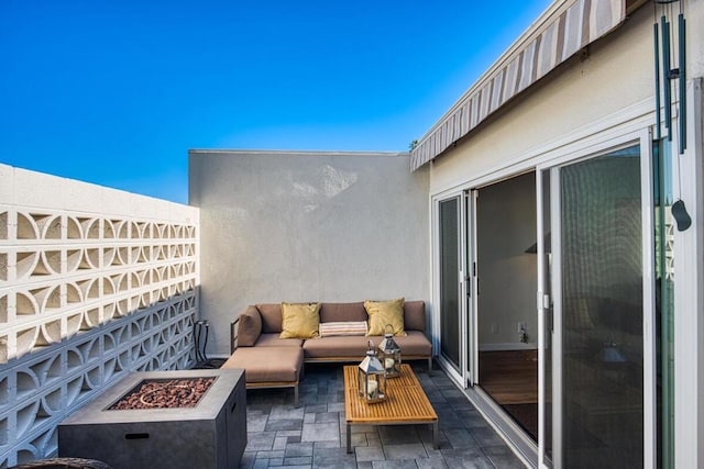 balcony featuring an outdoor living space with a fire pit and a patio area