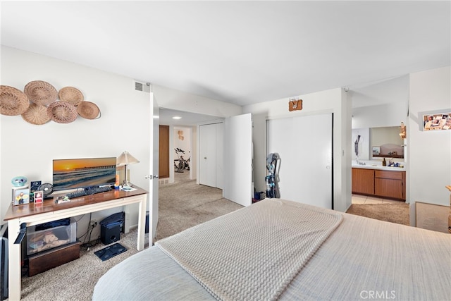 bedroom featuring light carpet, a closet, and ensuite bathroom