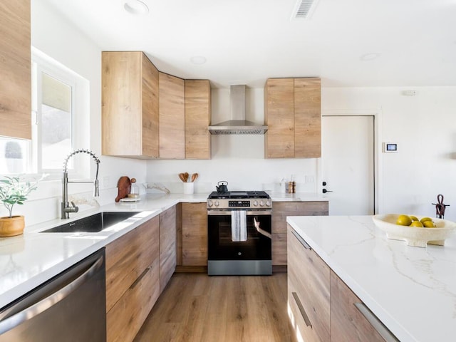 kitchen featuring light wood-type flooring, sink, wall chimney range hood, and stainless steel appliances