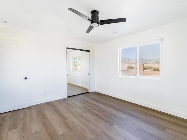 unfurnished bedroom featuring light wood-type flooring, ceiling fan, and a closet