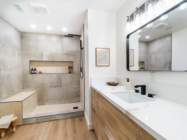 bathroom with a tile shower, hardwood / wood-style floors, and vanity