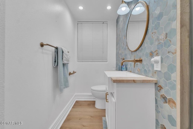 bathroom featuring toilet, vanity, tile walls, backsplash, and hardwood / wood-style floors