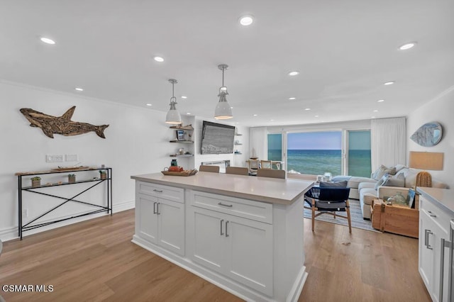 kitchen with decorative light fixtures, white cabinets, light hardwood / wood-style flooring, and a center island