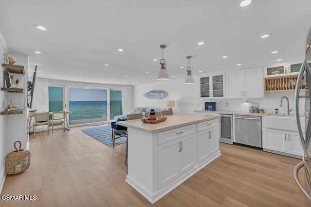 kitchen featuring a water view, white cabinetry, stainless steel dishwasher, and hanging light fixtures