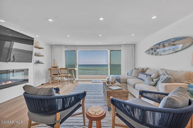 living room with light hardwood / wood-style floors, a water view, and a fireplace