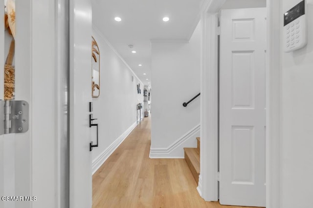 hallway with ornamental molding and light hardwood / wood-style flooring