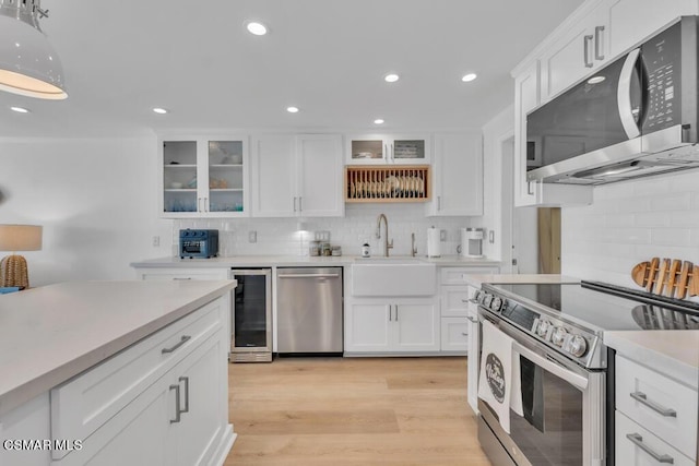 kitchen featuring appliances with stainless steel finishes, light hardwood / wood-style floors, wine cooler, and white cabinets