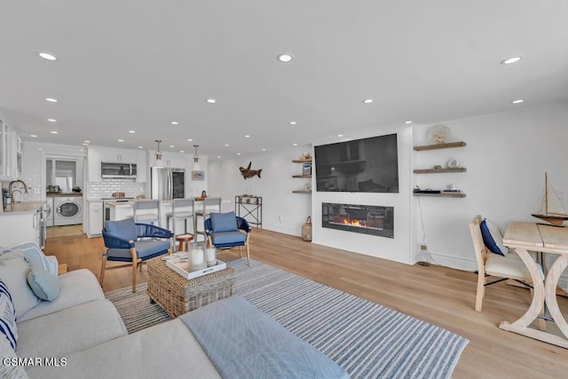 living room with a fireplace, light hardwood / wood-style floors, and washer / clothes dryer